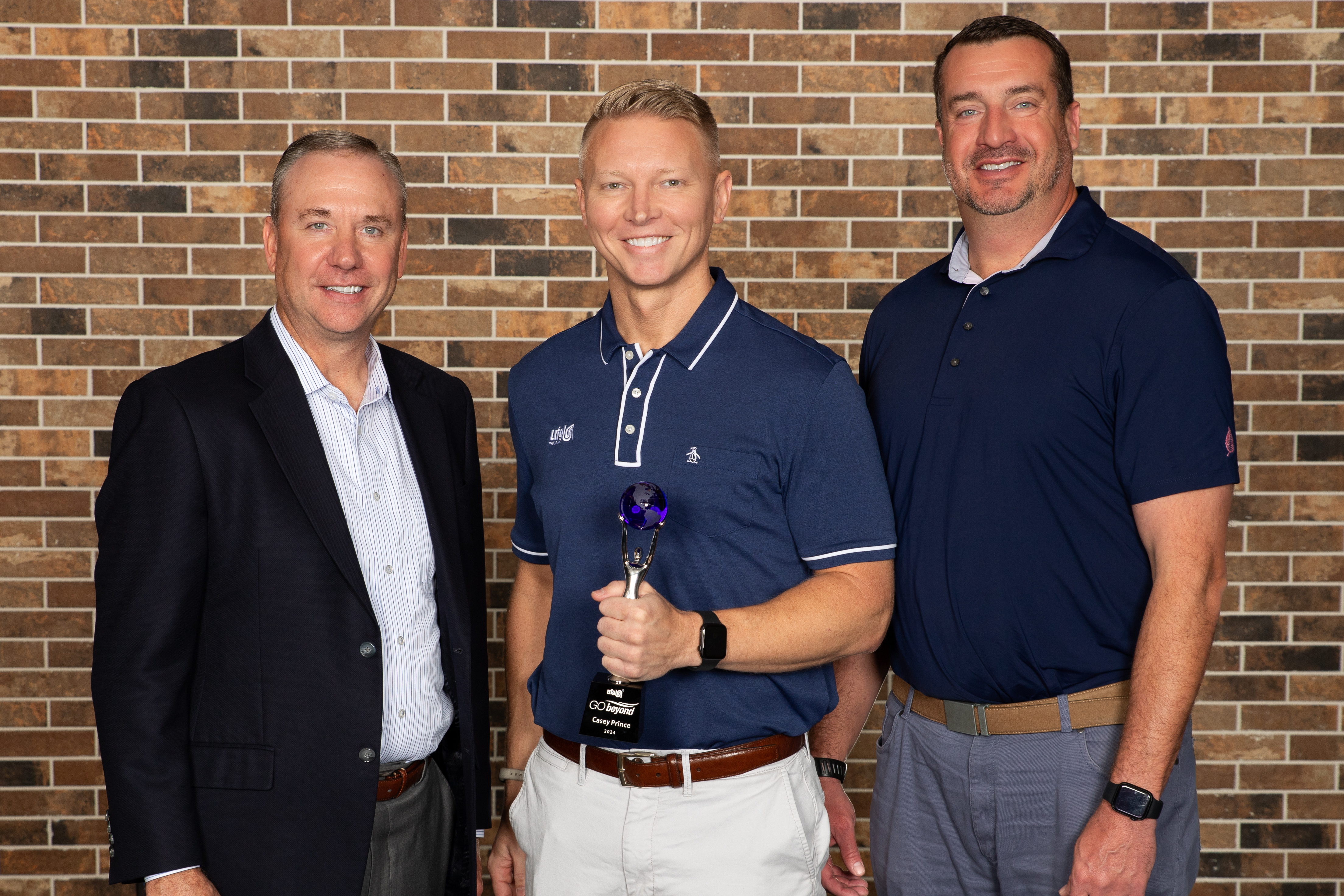 Men smiling at camera, celebrating an award.