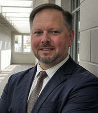 Man smiling in suit and tie.