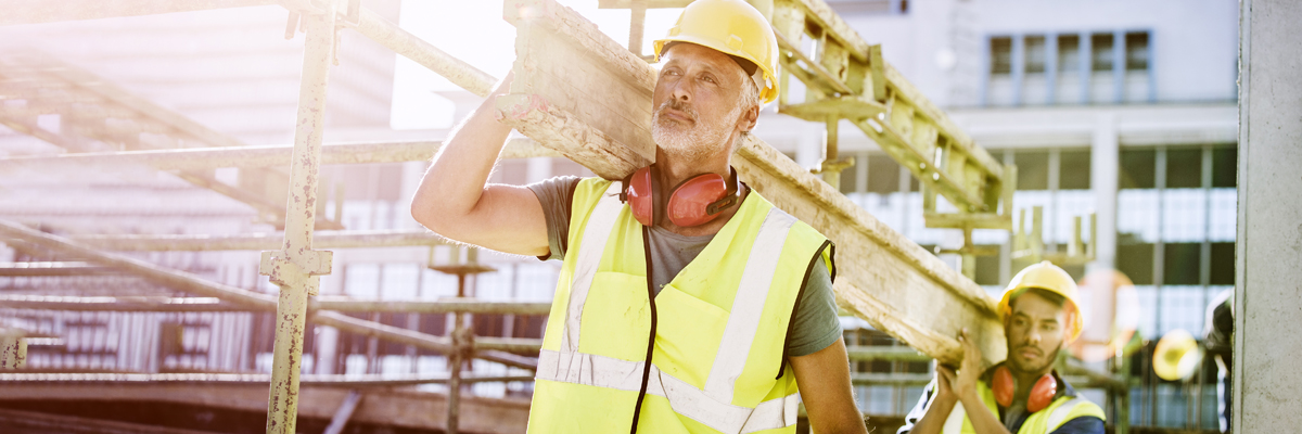 Construction worker carrying wooden beam at construction site. Construction worker carrying wooden beam at construction site.